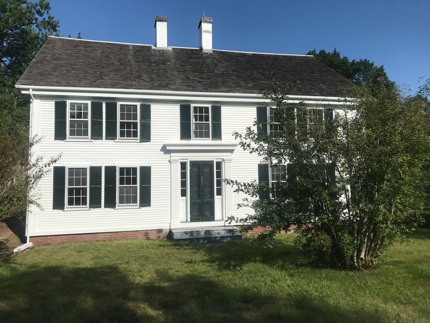 Two story Colonial house painted white with double chimneys.