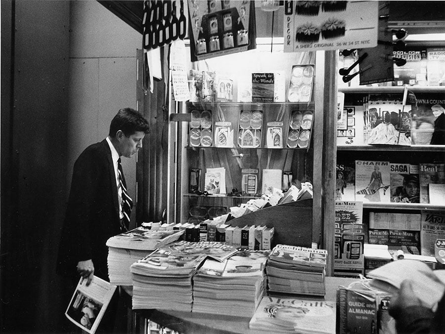 Man in suit looking at magazine at a newsstand