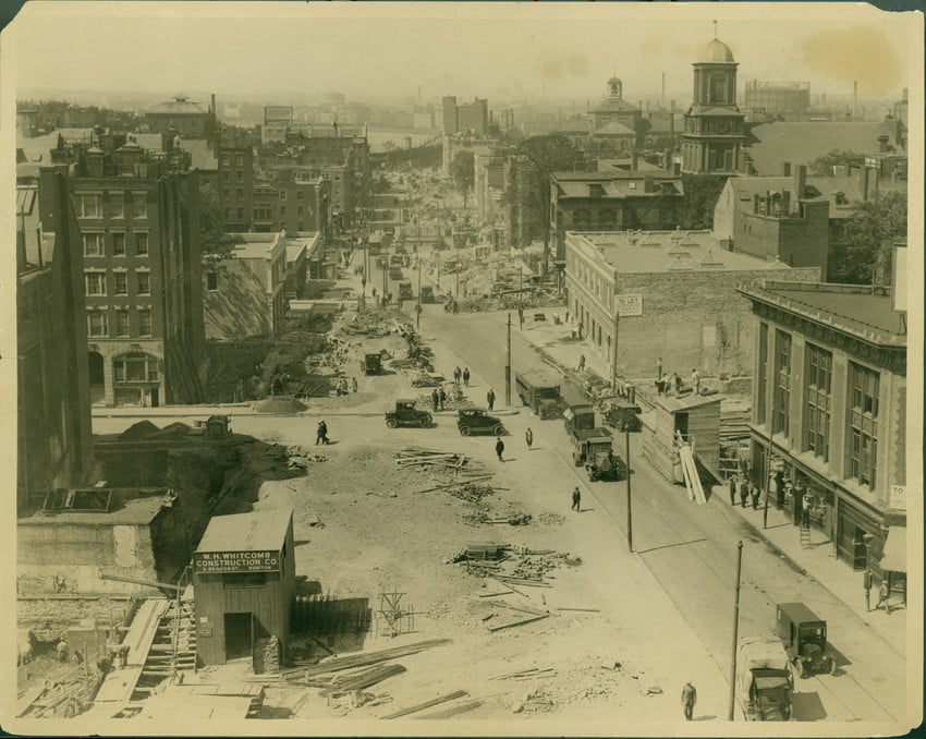 Historic urban street under construction with early automobiles and pedestrians. Transcribed Text: W. W. Whitcomb Construction Co.