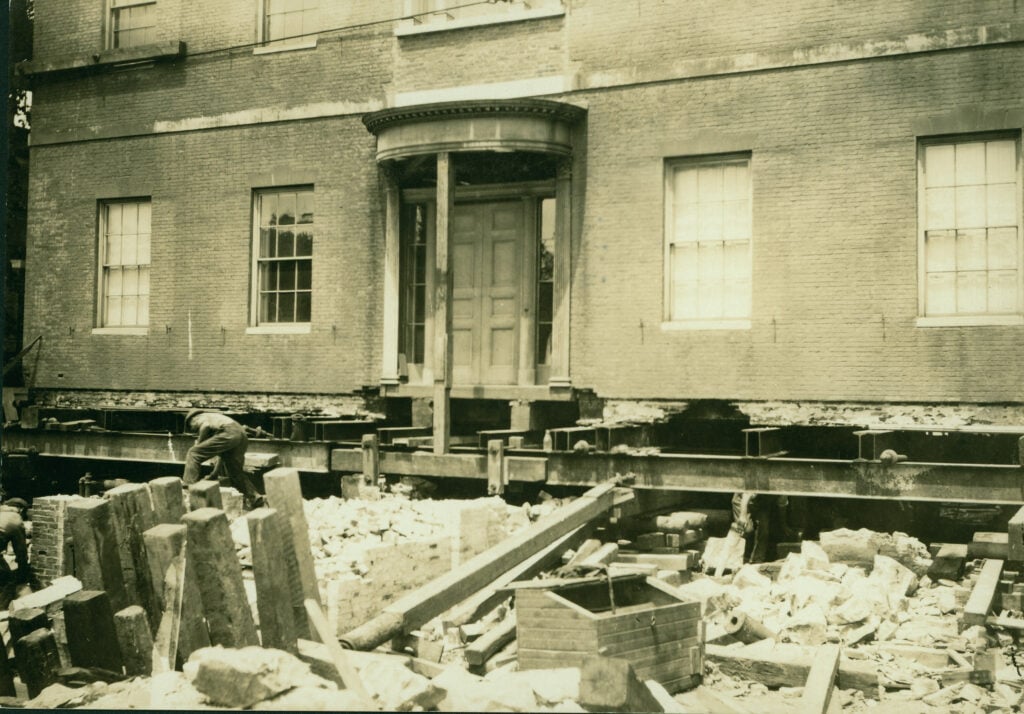 A brick building with visible foundation work and construction debris.